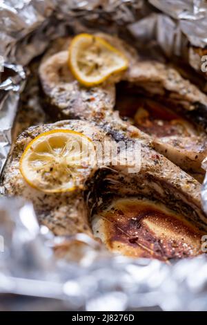 Gebackene Silberkarpfen-Steaks. Im Ofen in Folie mit Zitrone und Gewürzen gegartes Fischstück. Stockfoto