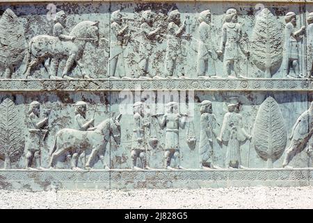 Persepolis, Iran - Wandrelieftafel mit Tribute-Prozession, Osttreppe der Apadana (Audienz-Halle), begonnen von Darius und beendet von Xerxes, befindet sich in den Ruinen der alten Stadt Persepolis, zeremonielle Hauptstadt des Achämenidenreiches, in der Provinz Fars, Iran. Archivbild aus dem Jahr 1976 Stockfoto