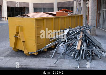 Riesiger Haufen auf Metall großer, überladener Müllcontainer, gefüllt mit Bauabfällen, Trockenbau und anderen Schutt in der Nähe einer Baustelle. Stockfoto