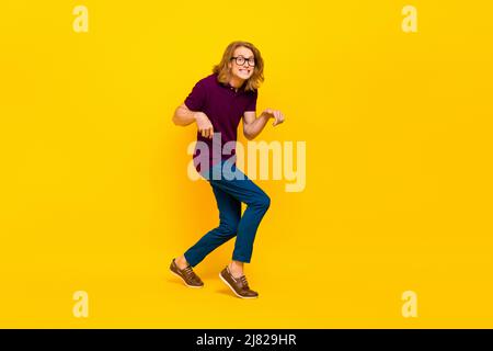 In voller Größe Porträt der positiven fröhlichen Person hinterhältig zu Fuß toothy Lächeln auf gelbem Hintergrund isoliert Stockfoto