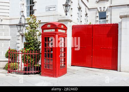 Traditionelle rote britische Telefonbox K2, entworfen von Sir Gilbert Gilbert Scott, neben einem roten Tor an der Farringdon Road, Clerkenwell, London, Großbritannien Stockfoto