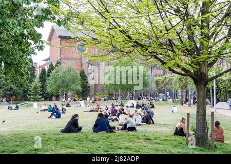 Menschen, die in Spa Fields in Clerkenwell, London, Großbritannien, zu Mittag essen, während das Wetter sich erwärmt Stockfoto