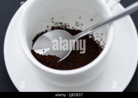 Nahaufnahme des gemahlenen Kaffees in einer Tasse mit Löffel Stockfoto
