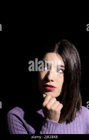 Nachdenkliche Brünette Frau mit schwarzem Hintergrund Stockfoto