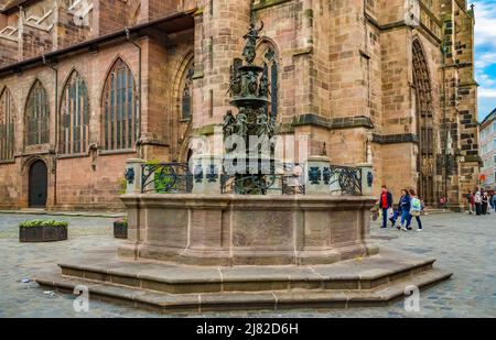 Schöner Blick auf den berühmten Tugendbrunnen aus Bronze der Spätrenaissance an der Westfassade der Kirche St. Lorenz in Nürnberg. Die sieben... Stockfoto