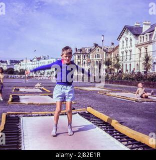 Ein kleiner Junge springt 1965 auf einem Trampolin in Teignmouth, Großbritannien, auf und ab. Stockfoto