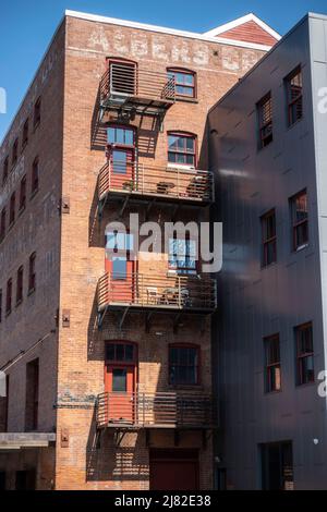 Tacoma, WA USA - ca. August 2021: Blick aus der Nähe einer Holztreppe auf der Außenseite eines roten Backsteingebäudes, die zu verschiedenen Ebenen einer apa führt Stockfoto