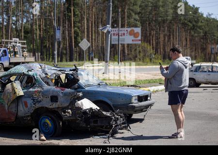 Irpin, Ukraine. 10.. Mai 2022. Auf dem Autofriedhof sieht man einen Zivilisten, der mit seinem Handy fotografiert. Ein Parkplatz in Irpin wurde im März zu Beginn des russisch-ukrainischen Krieges zu einem Autofriedhof für alle beschädigten Fahrzeuge durch die russische Armee umgeschlagen, um die Stadt zu belagern und Kiew zu erobern. Russland marschierte am 24. Februar 2022 in die Ukraine ein und löste damit den größten militärischen Angriff in Europa seit dem Zweiten Weltkrieg aus (Foto von Hesther Ng/SOPA Images/Sipa USA) Quelle: SIPA USA/Alamy Live News Stockfoto