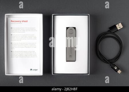 Russland, Krasnodar - 15. April 2022: Kryptowährung Hardware Wallet in Box, Recovery-Blatt und usb-Kabel auf dunklem Hintergrund. Sichere Speicherung für Krypto. Stockfoto