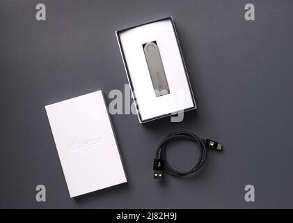 Russland, Krasnodar - 15. April 2022: Kryptowährung Hardware Wallet Ledger in Box mit usb-Kabel auf dunklem Hintergrund. Sichere Speicherlösung für Bitcoin. Stockfoto