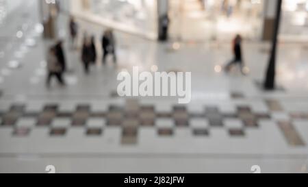 Verschwommenes Bild von Leuten, die in der Lobby des Einkaufszentrums herumlaufen. Hintergrundbild. Stockfoto