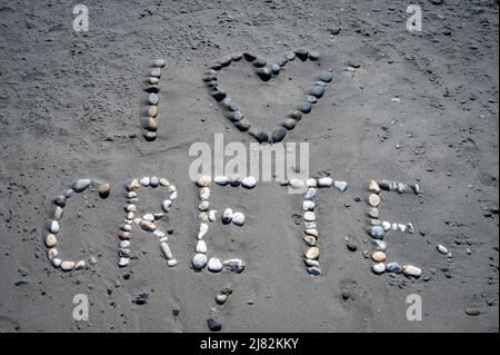 Ich liebe Kreta geschrieben am Sandstrand in Kreta, Griechenland. Text Ich liebe kreta mit Herzsymbol, geschrieben mit Kieselsteinen an einem Sandstrand im Sommer. Stockfoto