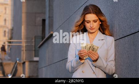 Erfolgreiche reiche kaukasische tausendjährige Geschäftsfrau auf der Straße Stadt im Freien Zählen Geld halten Dollar Banknoten Rechnung Budget zählen Gehalt Stockfoto