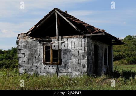 Ruiniertes und verlassenes altes Haus auf einem grünen Hügel Stockfoto