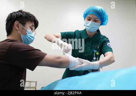 Peking, China. 12.. Mai 2022. Eine Krankenschwester verbindet die Wunde für einen Patienten in einem Krankenhaus im Bezirk Beibei im südwestchinesischen Chongqing, 12. Mai 2022. Die Zahl der registrierten Krankenschwestern in China ist in den letzten 10 Jahren mit einer durchschnittlichen jährlichen Rate von 8 Prozent auf 5,02 Millionen Ende 2021 gestiegen, teilte die Nationale Gesundheitskommission am Mittwoch vor dem Internationalen Krankenschwestern-Tag mit, der auf den 12. Mai fällt. Quelle: Qin Tingfu/Xinhua/Alamy Live News Stockfoto