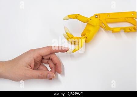 Frauenhand und eine Kunststoff-Handprothese für ein Kind auf weißem Hintergrund. Stockfoto