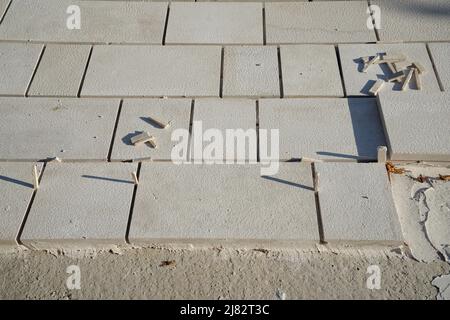 Verlegung von Pflasterplatten. Lassen Sie einen Spalt zwischen beiden, um mit einem Fugen oder Zementfüller zu füllen. In Bearbeitung. Stockfoto