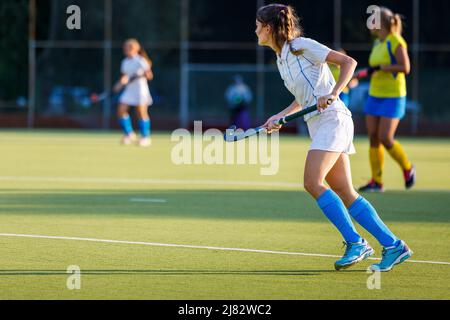 Junge Feldhockey-Spielerin mit Stock während des Spiels Stockfoto