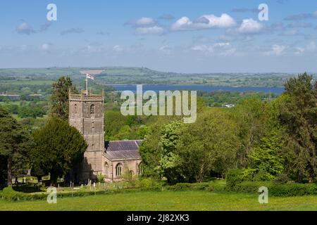 Die Kirche St. Michael des Erzengels im Dorf Compton Martin am Fuße der Mendip Hills mit dem Chew Valley Lake Reservoir im Jenseits, Somerset, England. Stockfoto