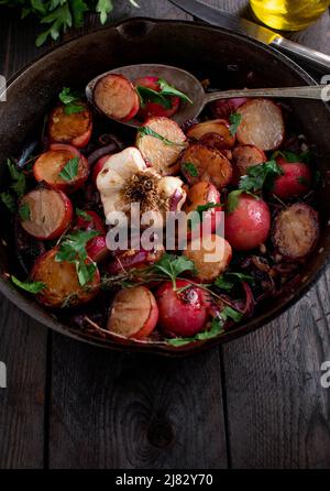 Gemüsebeilage mit karamellisiertem rotem Rettich. Gekocht mit spanischen Zwiebeln, Knoblauch und Parley. Stockfoto