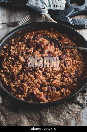 Gesundes Fitness-Essen mit einem veganen Muskelaufbaugericht, zubereitet mit braunem Reis, Nierenbohnen, Gemüse und Tomatensauce. Stockfoto