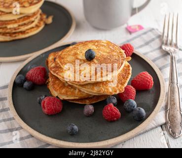 Protein-Pfannkuchen frisch und hausgemacht mit Instant-Hafer, Quark und Eiern. Zum Frühstück auf einem Teller mit frischen Beeren serviert Stockfoto