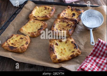 Süße Blätterteigtörtchen mit Sauerrahm, Eigelb, Zucker, Zitronenfüllung auf einem Backblech Stockfoto