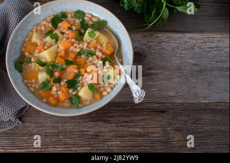 Vegane Bohnensuppe mit Gemüse und Kartoffeln. Serviert in einer Schüssel mit Löffel auf Holztisch. Overhead-Ansicht mit Kopierbereich Stockfoto