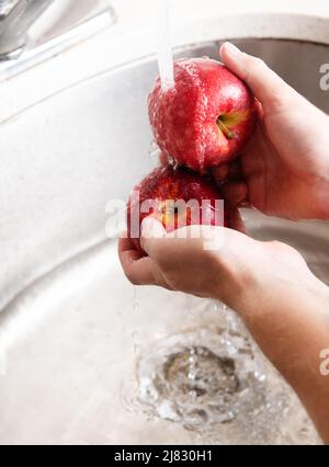 Roter Apfel wird im Waschbecken gewaschen Stockfoto