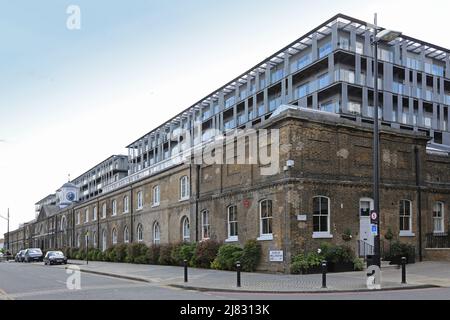 Duke of Wellington Avenue, Woolwich, Southeast London, Großbritannien. Zeigt viktorianisches Hafengebäude, überschattet durch neue Wohnsiedlung dahinter. Stockfoto