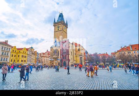 PRAG, TSCHECHISCHE REPUBLIK - 5. MÄRZ 2022: Der Uhrturm des Alten Rathauses vom Altstädter Ring mit bunten Stadthäusern und vielen Touristen, am März Stockfoto