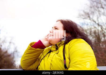 Attraktive mollige übergewichtige kaukasische Frau lächelnd Porträt im Freien mit Kopieplatz. Fröhliche hübsche Körper positive Person während des Spaziergangs im Park. Stockfoto