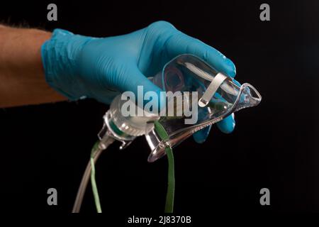 Arzthand mit Einweg-Sauerstoffmaske zur Unterstützung der Atmung Stockfoto