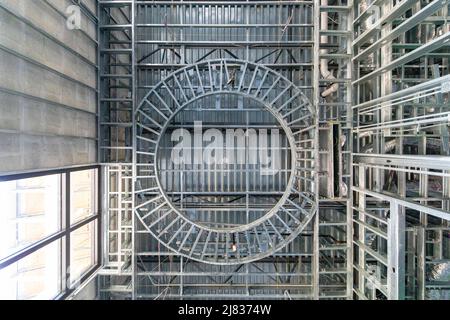 Rahmenkonstruktionen aus verzinktem Stahl in der Lobby eines im Bau befindlichen Apartmentkomplexes. Stahl über Beton mit geraden Linien und einem Kreis Stockfoto