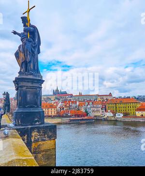 Die alte Skulptur des Hl. Johannes des Täufers auf der Karlsbrücke mit der Moldau, die roten Dächer des Mala Strana Bezirks und die St. Veits Kathedrale in der Stockfoto