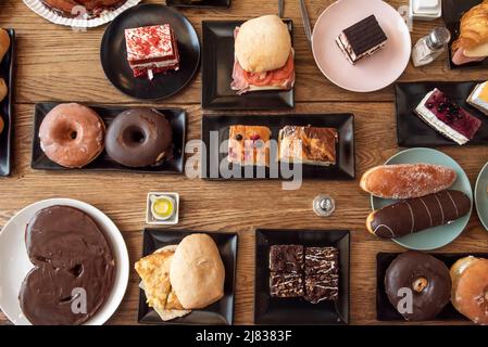 Overhead-Bild von Sandwiches, Donuts, Gebäck, Kuchen und Süßigkeiten zum Frühstück und Snack, viel Schokolade, venezolanische Croissants, Croissants mit ch Stockfoto