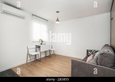 Studio-Apartment mit Metall und weiß madra faltbaren zwei-Sitzer-Esstisch mit passenden Stühlen unter durchsichtigen Blind-Windo Stockfoto