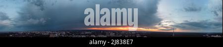 Dramatischer, ultrabreiter Blick auf die Wolkenlandschaft bei Sonnenuntergang im Wohnviertel der Stadt. Luftaufnahme Pavlovo Pole, Charkiw Ukraine. Abendhimmellandschaft, Wolkenlandschaft w Stockfoto