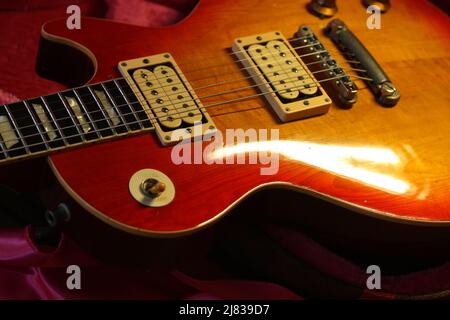 Foto von vintage Les Paul Gitarrenkörper, zeigt Abnutzung von Lack. Die Gitarre ist auf einem gegerbten Etui mit rosafarbenem Filzinterieur platziert. Stockfoto