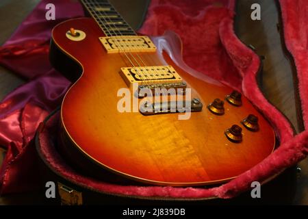 Foto von vintage Les Paul Gitarrenkörper, zeigt Abnutzung von Lack. Die Gitarre ist auf einem gegerbten Etui mit rosafarbenem Filzinterieur platziert. Stockfoto