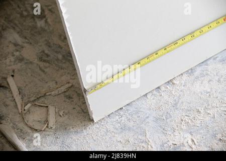 Ein Stück Drywall / Sheetrock wird zum Schneiden und Installieren vermessen Stockfoto