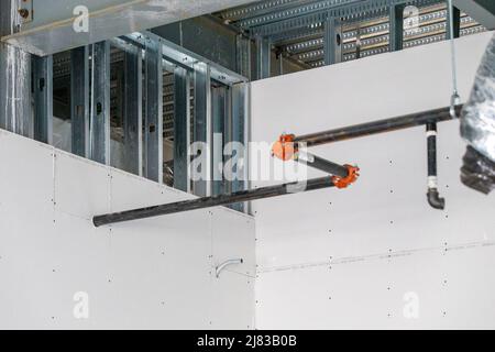 Die Ecke eines Raums in einem Geschäftsgebäude, das mit teilweise installierter Trockenmauer und einer verzinkten Stahlrahmenkonstruktion gebaut wird. Stockfoto