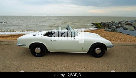 Klassisches weißes Lotus Cabriolet, das am Strandpromenade und am Meer im Hintergrund geparkt ist. Stockfoto