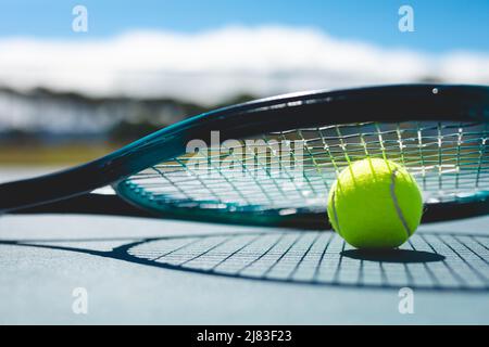 Nahaufnahme des grünen Tennisballs mit Schläger auf dem Platz am sonnigen Tag Stockfoto