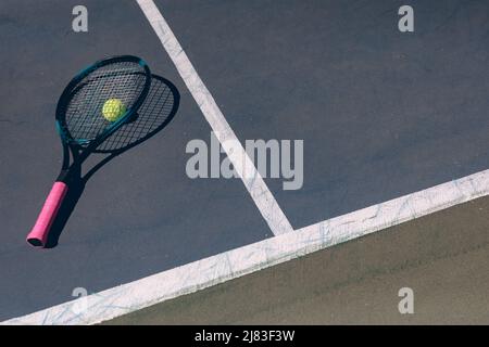 Blick auf den Tennisschläger auf dem Ball und dem Platz mit Linien an sonnigen Tagen Stockfoto