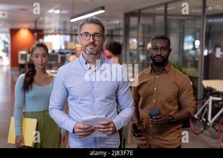 Porträt selbstbewusster, multirassischer Unternehmensberater, die am modernen Arbeitsplatz zusammenstehen Stockfoto