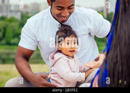 Transnationale interracial Mutter und Vater zu Fuß mit ihrem gemischten Rennen Baby Mädchen im Herbst Park, erste Schritte Stockfoto