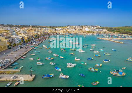 Luftpanorama von Marsaxlokk - kleines, traditionelles Fischerdorf in der südöstlichen Region von Malta mit vielen bunten Fischerbooten Stockfoto