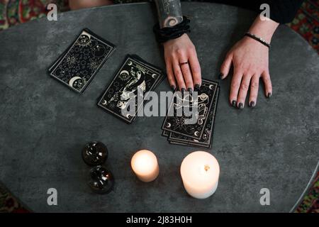 Aus der oberen Ansicht Aufnahme einer geheimnisvollen reifen Frau, die sich für die Eoterik interessiert und Tarot-Karten liest Stockfoto