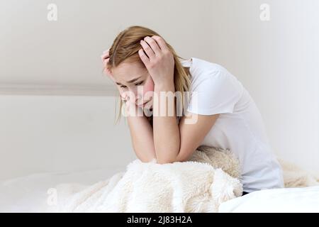 Depressive Frau erwacht in der Nacht und leidet an Schlaflosigkeit. Konzept der Einsamkeit und des Schmerzes. Unglückliche Frau, die zu Hause auf dem Bett sitzt, psychologisch und m Stockfoto